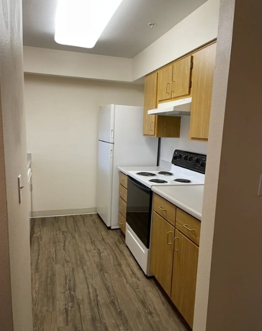 A kitchen with a white refrigerator, white stove, and wooden cabinets.