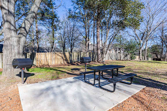 two picnic tables and two barbecue pits in a park