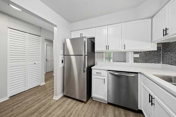 A modern kitchen with white cabinets and a stainless steel refrigerator.