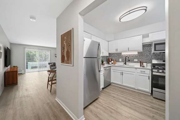 A modern kitchen with stainless steel appliances and wooden flooring.