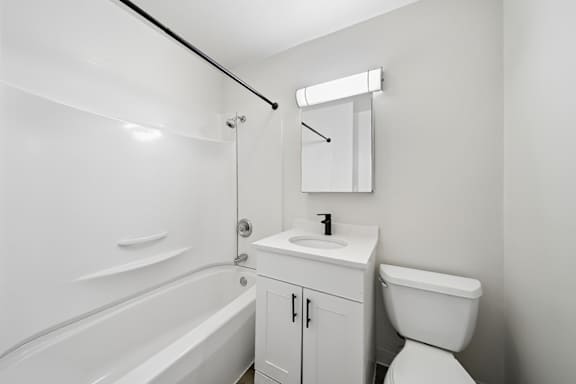 A white bathroom with a tub, sink, and toilet.