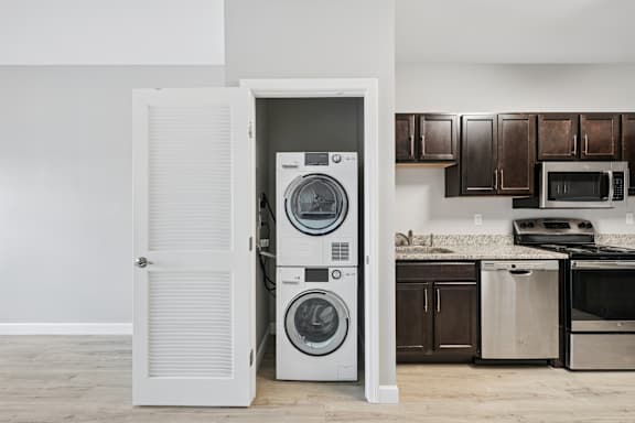 A white door is open to reveal a stack of washers and dryers.