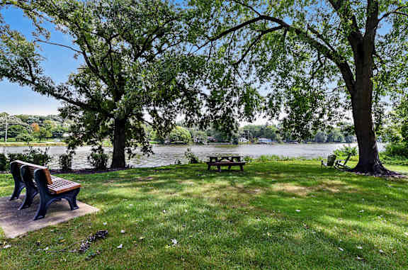 a park with benches and a picnic table near a river at The View Apartments St Charles, St Charles, IL
