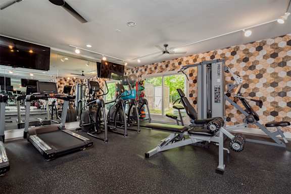 a gym with weights and cardio equipment and a television  at Ascent at Farmington Hills, Farmington Hills, MI
