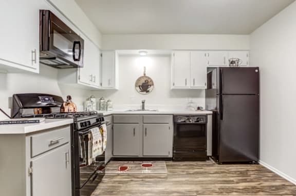 A kitchen with white cabinets and a black refrigerator.