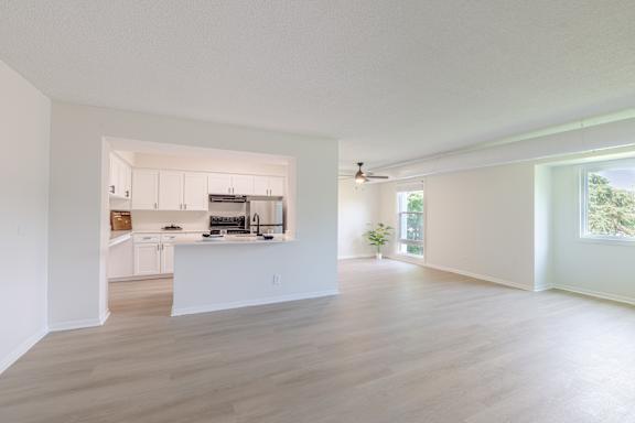 A spacious, empty room with light wood flooring and white walls.