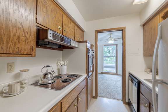 A kitchen with wooden cabinets and a stove top oven.
