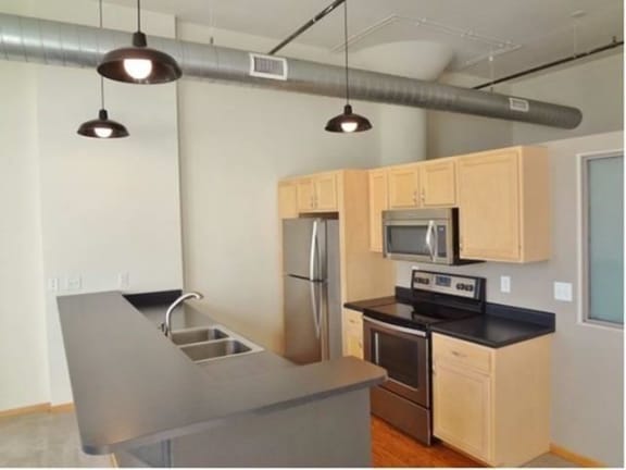 A kitchen with a stainless steel sink and black countertop.