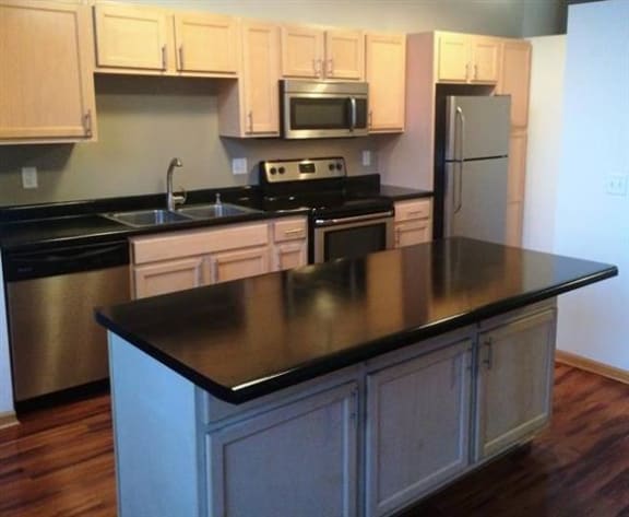 A kitchen with a black counter top and wooden cabinets.