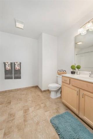 A bathroom with a toilet, sink, and mirror.