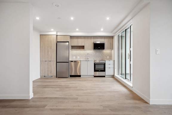 A modern kitchen with wooden floors and stainless steel appliances.