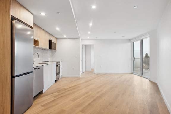 A modern kitchen with wooden floors and stainless steel appliances.