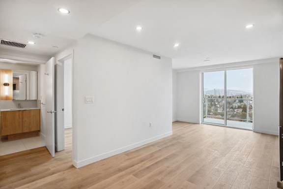 A spacious room with wooden flooring and white walls.