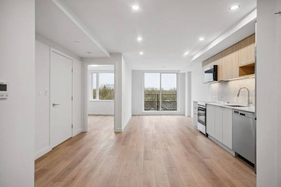 A modern kitchen with wooden floors and white walls.