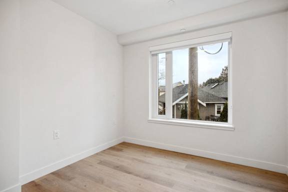 A room with a window showing a view of houses across the street.