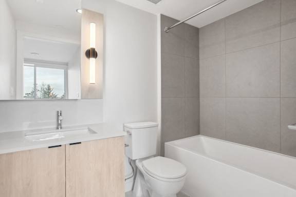 A modern bathroom with a white toilet and a white bathtub.