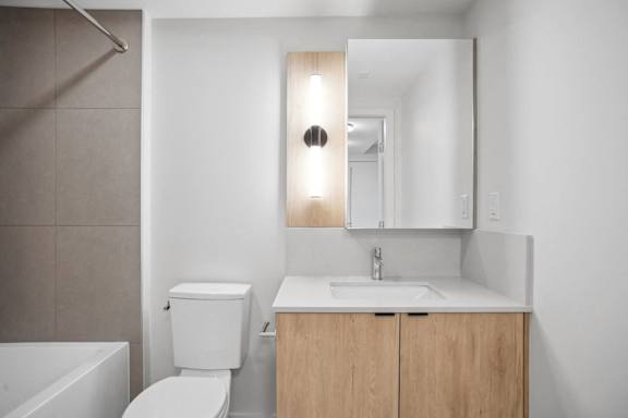 A bathroom with a toilet, sink, and mirror.