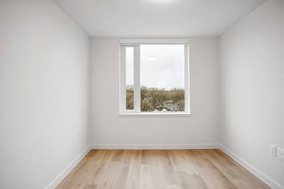 A room with a window and wooden flooring.