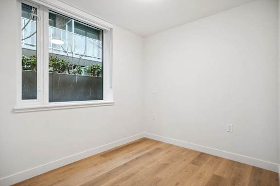 A room with a window and wooden flooring.