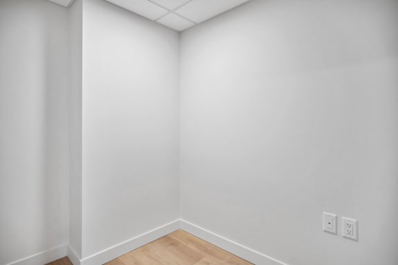 A white wall with a switchboard and a wooden floor.