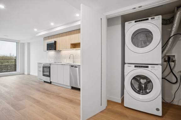 A modern kitchen with a washing machine stacked on top of another.