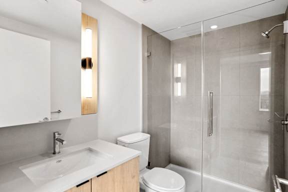 A modern bathroom with a white sink and a walk-in shower.