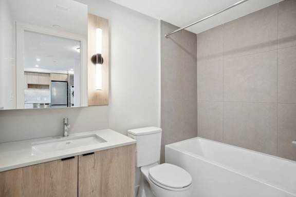 A modern bathroom with a white toilet, sink, and bathtub.