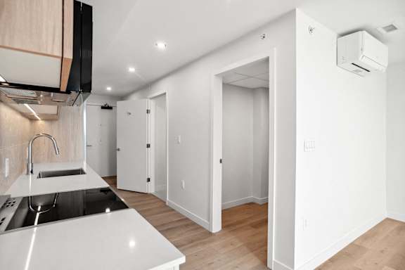 A modern kitchen with white countertops and a stainless steel sink.