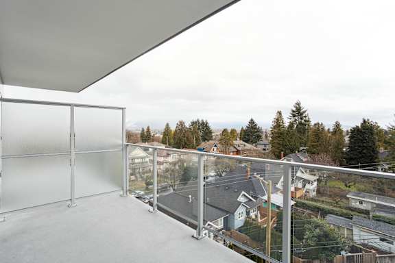 A balcony with a glass railing overlooking a residential area.