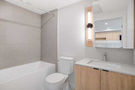 A white toilet sits next to a white bathtub in a bathroom.