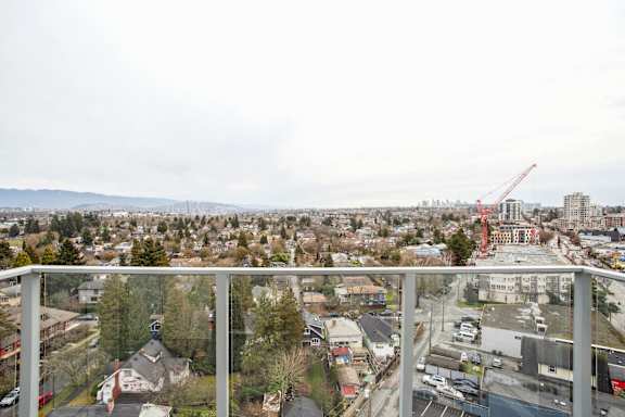 A view from a balcony overlooking a city with a crane in the distance.