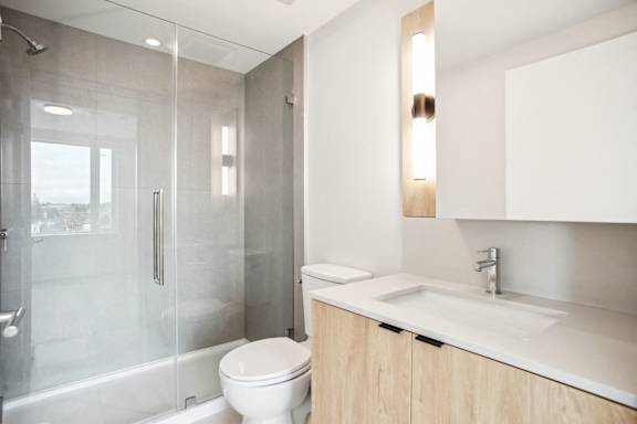 A modern bathroom with a toilet, sink, and shower.
