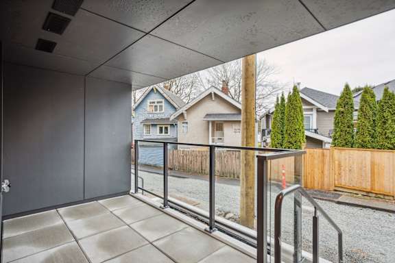 A view from a covered balcony looking out at a residential street.