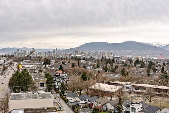 A cityscape with buildings, trees, and mountains in the distance.