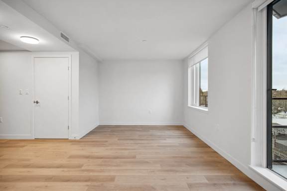 A room with wooden flooring and white walls.