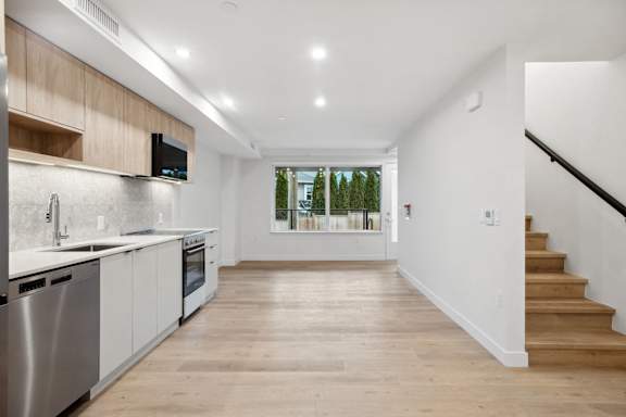 A modern kitchen with wooden floors and stainless steel appliances.