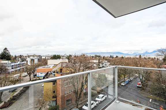 A balcony overlooks a parking lot and buildings.