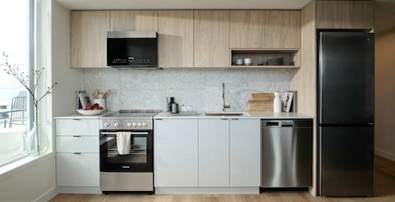 A modern kitchen with a black fridge and stainless steel appliances.