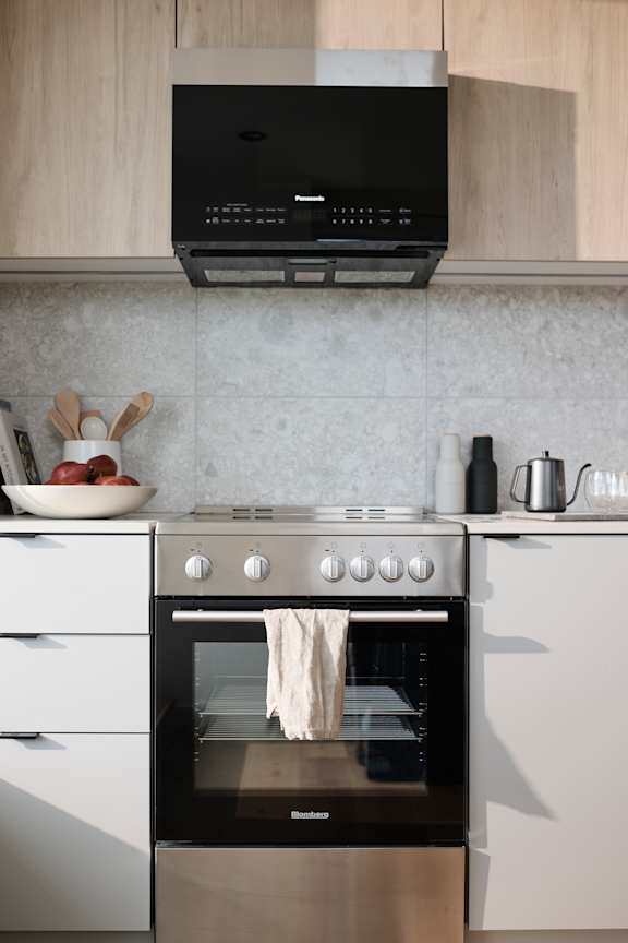 A modern kitchen with a black oven and white cabinets.