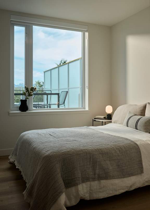 A bedroom with a large bed and a window overlooking a balcony.
