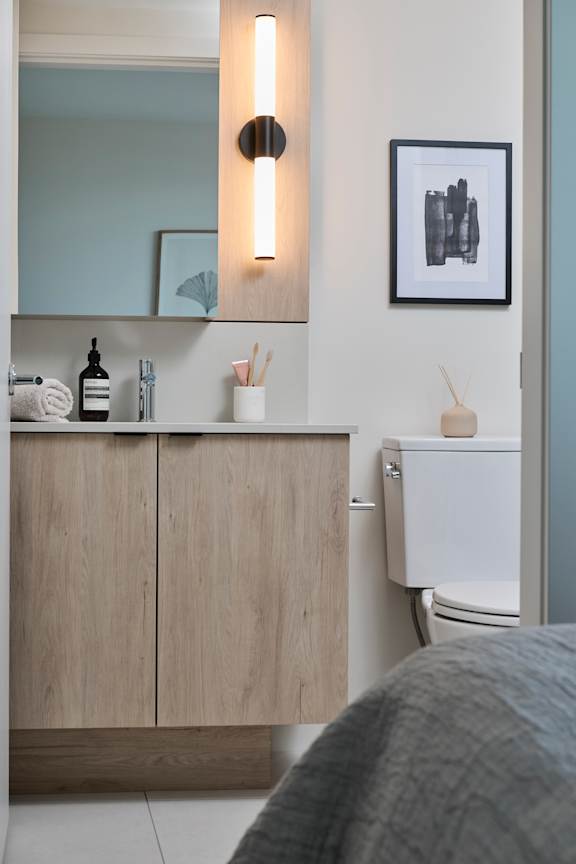 A bathroom with a toilet, a cabinet, and a framed picture on the wall.