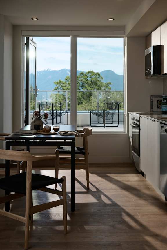 A kitchen with a table and chairs in front of a window with a view of the mountains.