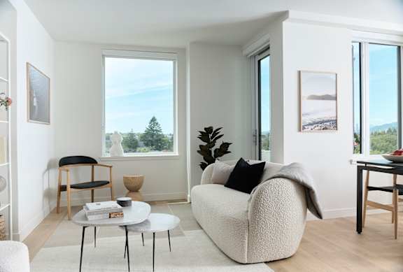 A living room with a white couch and a table with a bowl on it.
