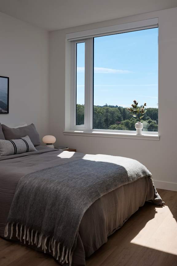 A bedroom with a large bed and a window overlooking a landscape.