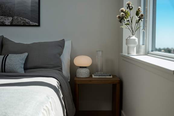 A bedroom with a bed, nightstand, and a window.