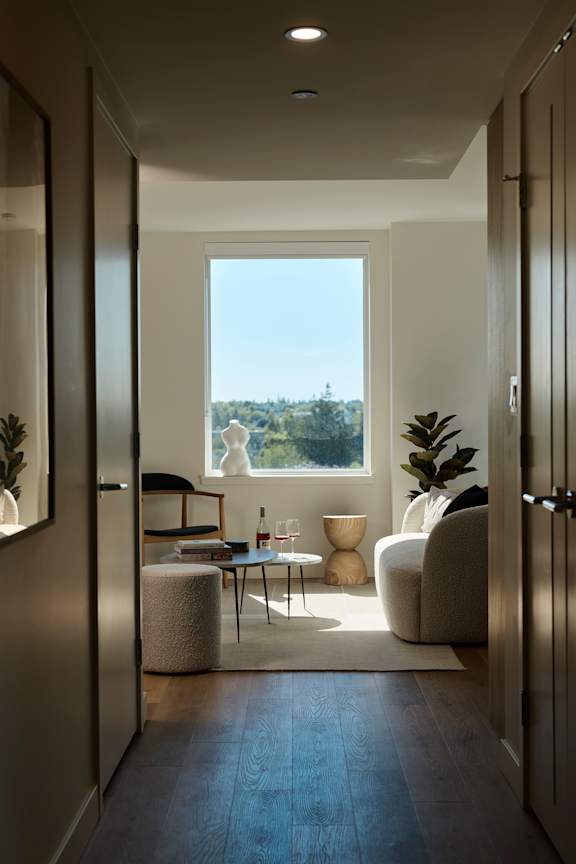 A modern living room with a view of the trees outside the window.
