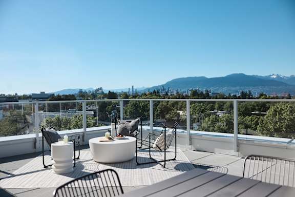A patio with a table and chairs overlooking a cityscape.