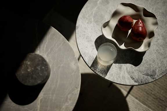 A glass plate with two apples and a candle on a table.