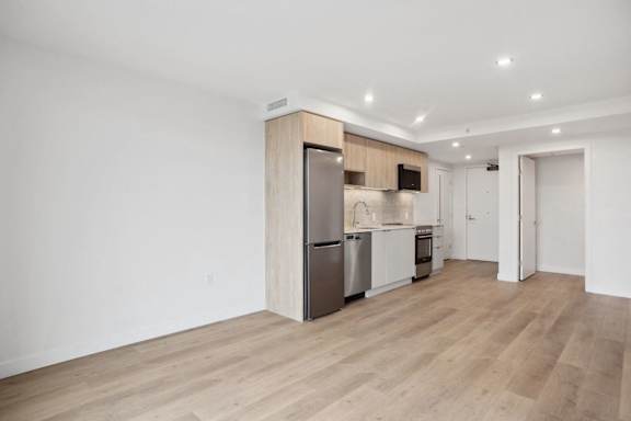 A kitchen with a refrigerator, oven, and microwave.