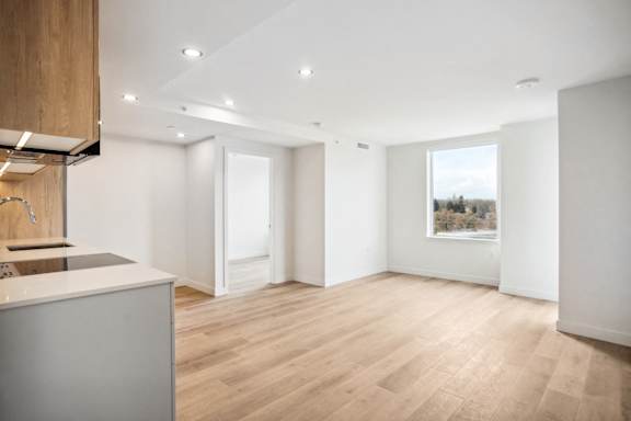 A spacious room with wooden flooring and white walls.